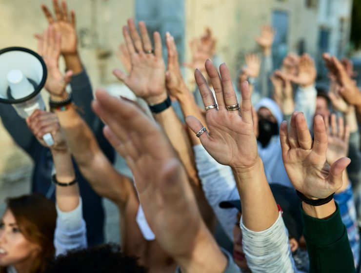 Close-up of crowd of protesters with arms raised demonstrating on the streets.